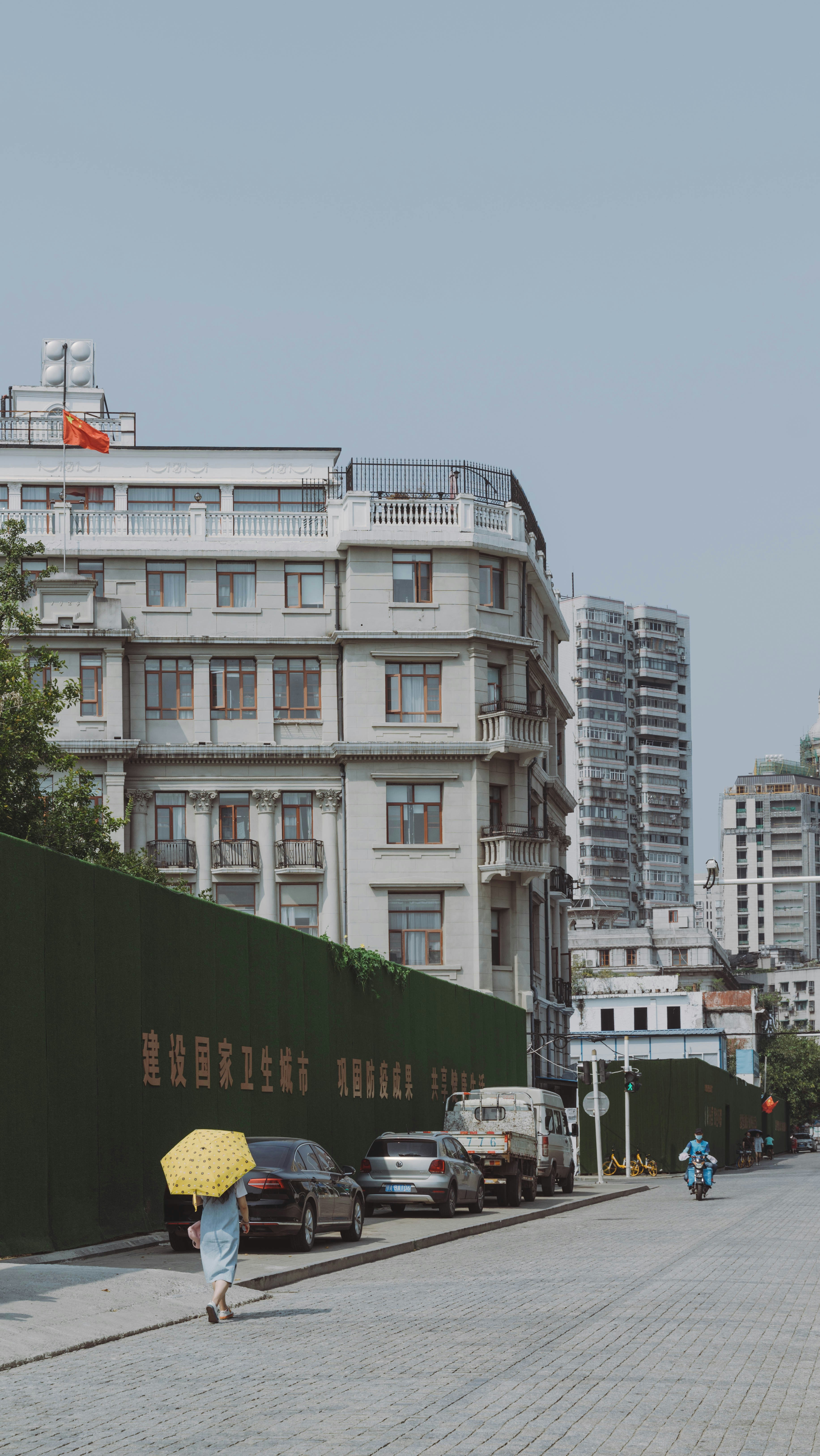 a woman walking down a street holding a yellow umbrella