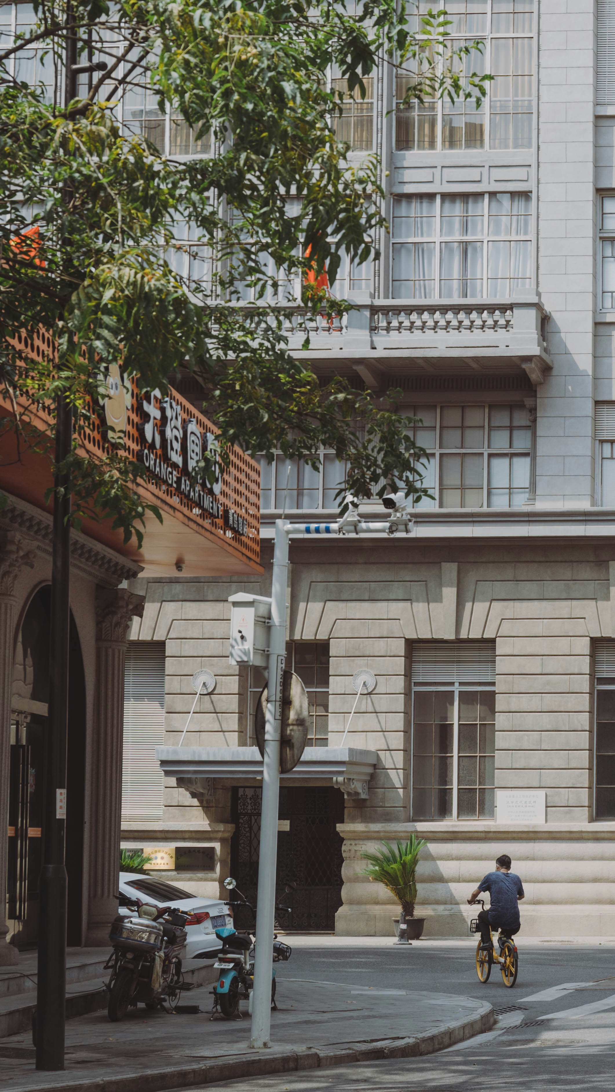 a man riding a bike down a street next to a tall building