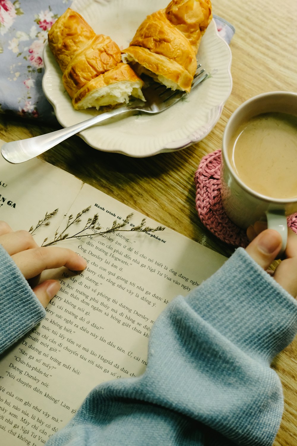 a person sitting at a table with a book and a cup of coffee