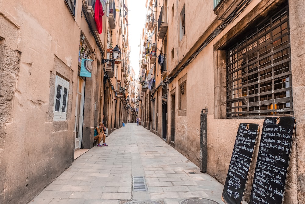 a narrow city street with a sidewalk lined with buildings