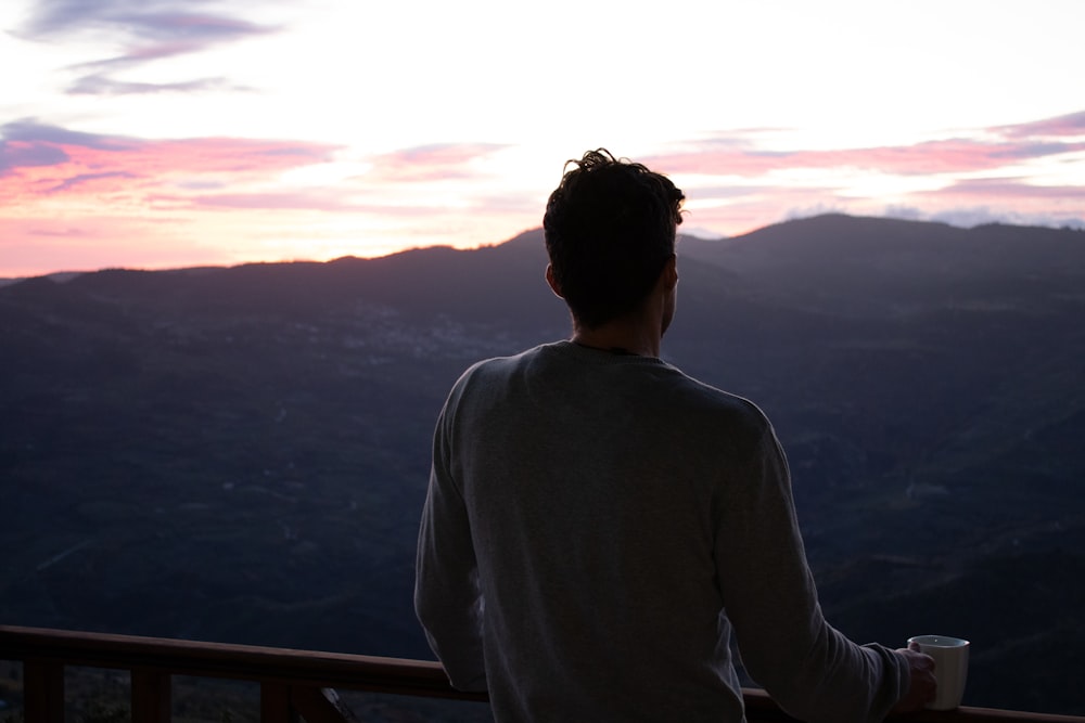 a man standing on a balcony with a cup of coffee