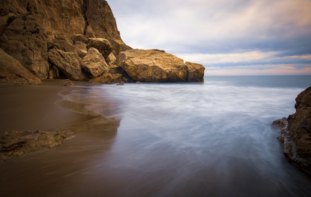 a long exposure photo of the ocean and rocks