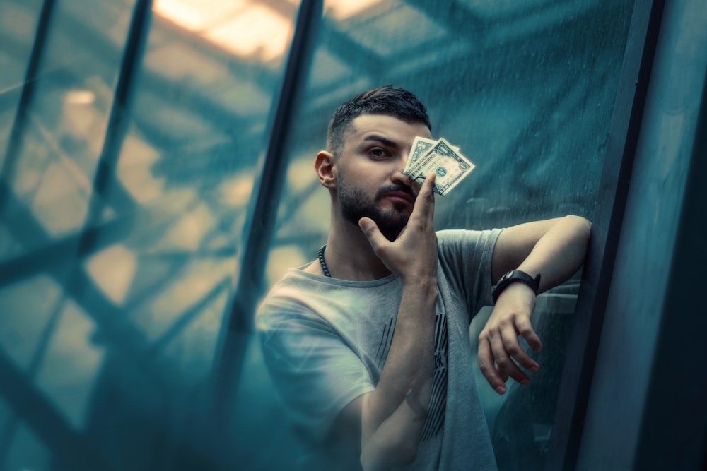 a man leaning against a glass wall talking on a cell phone