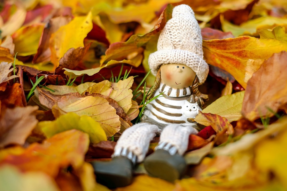 a small toy sitting on top of a pile of leaves