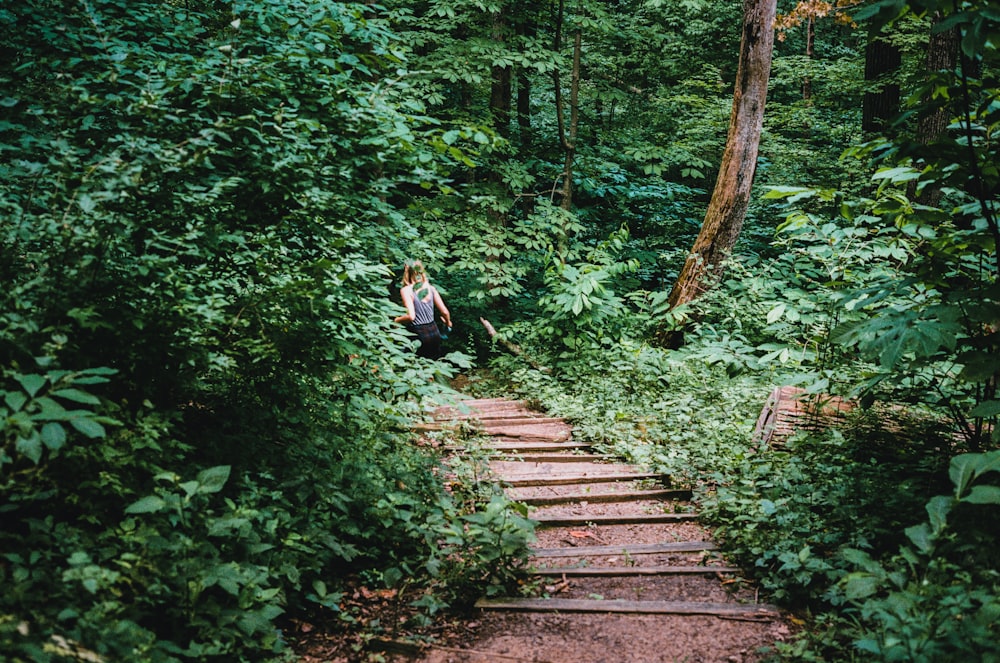 a woman is sitting on a set of stairs in the woods