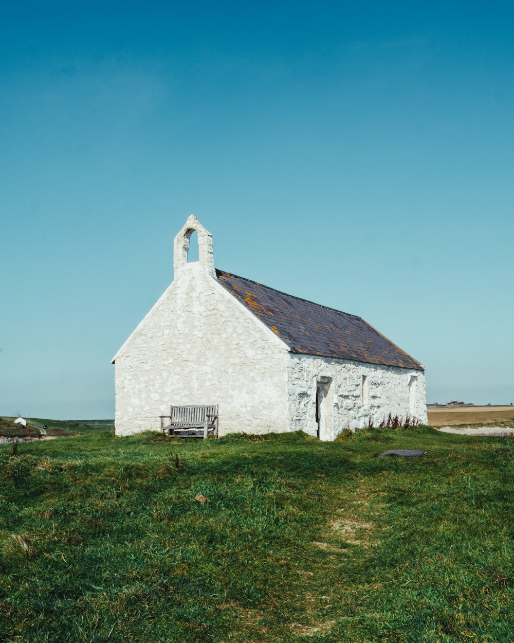 a white church with a bench in front of it