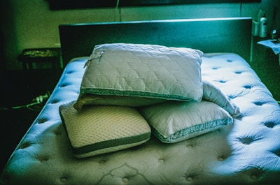a pile of pillows sitting on top of a bed