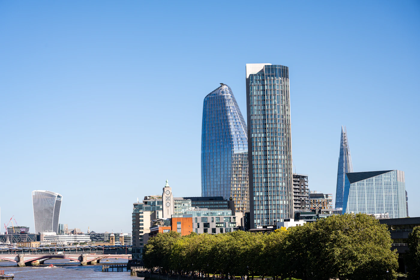 Office towers in central London, including the Shard, seen across the Thames under a clear sky