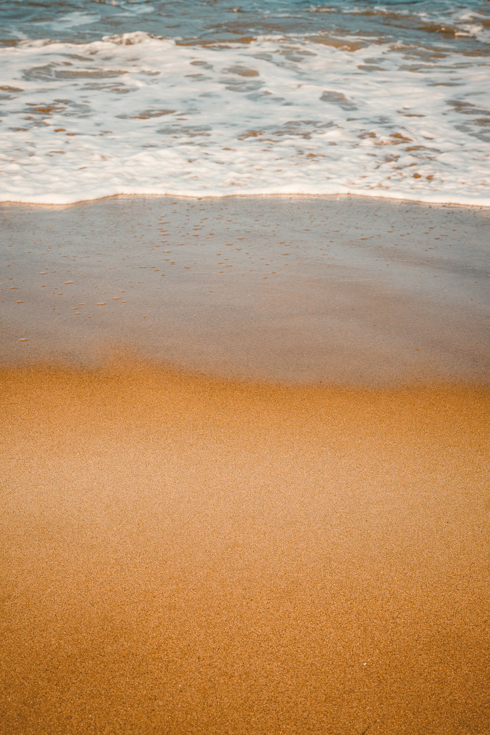 a sandy beach next to the ocean with waves coming in