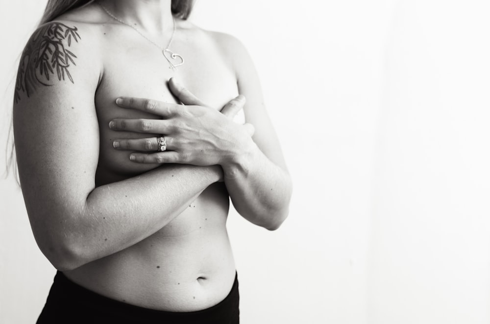 a black and white photo of a woman with tattoos on her chest