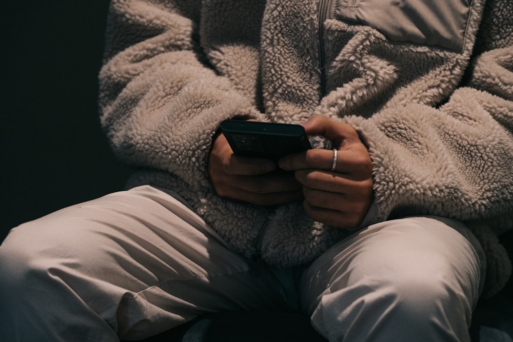 a person sitting down holding a cell phone