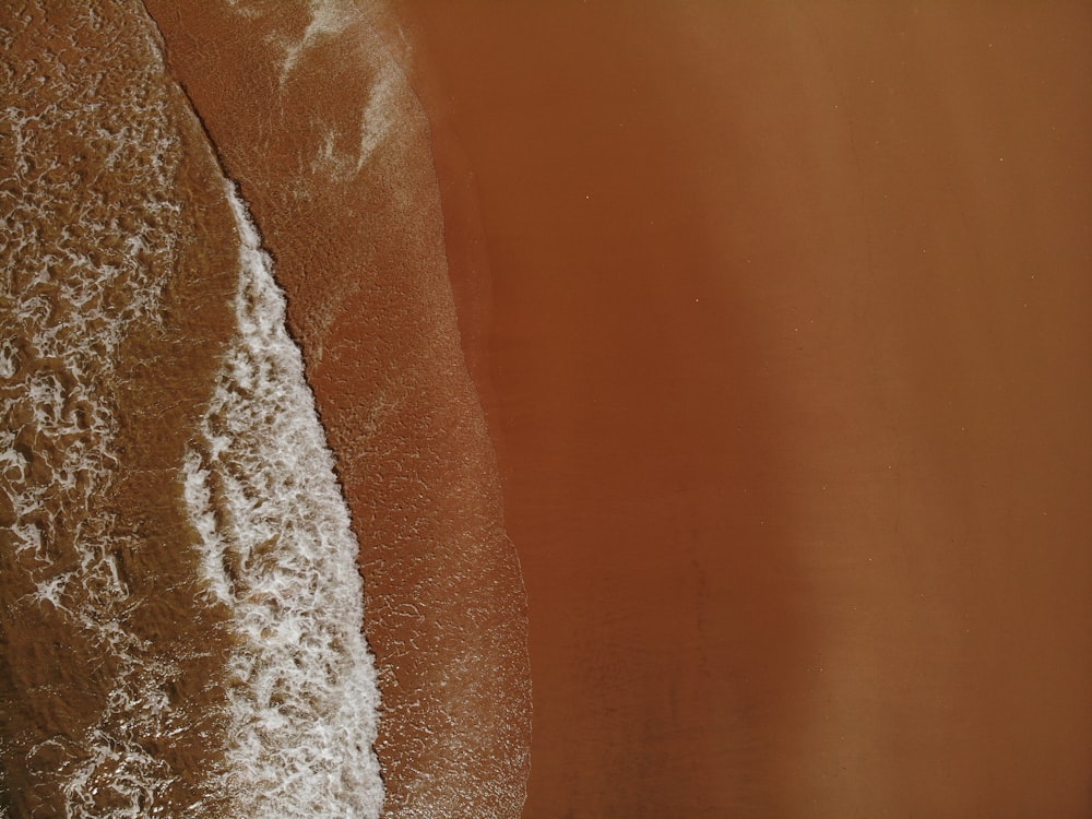 an aerial view of a sandy beach with waves