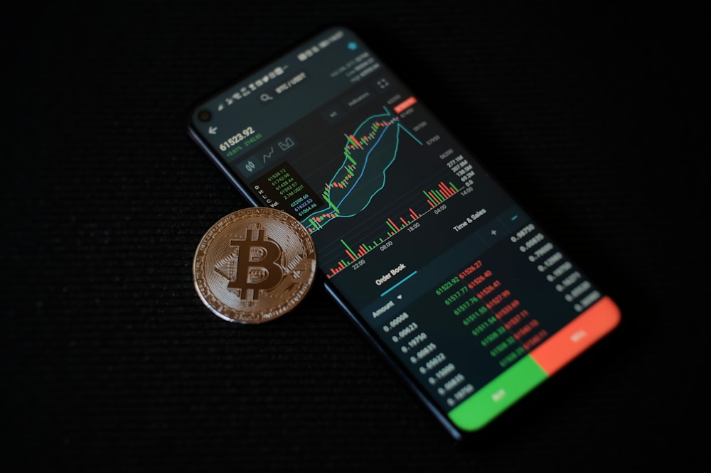 a bitcoin sitting on top of a smart phone