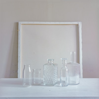 Minimalist still life featuring Nouveau Water bottles arranged on a smooth white surface.