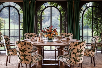 a dining room table with chairs and a vase of flowers