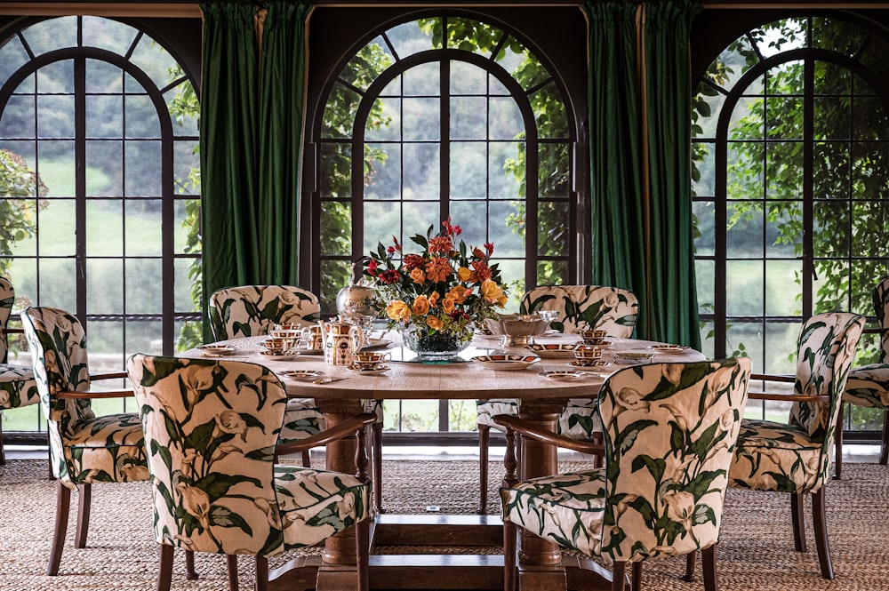 a dining room table with chairs and a vase of flowers