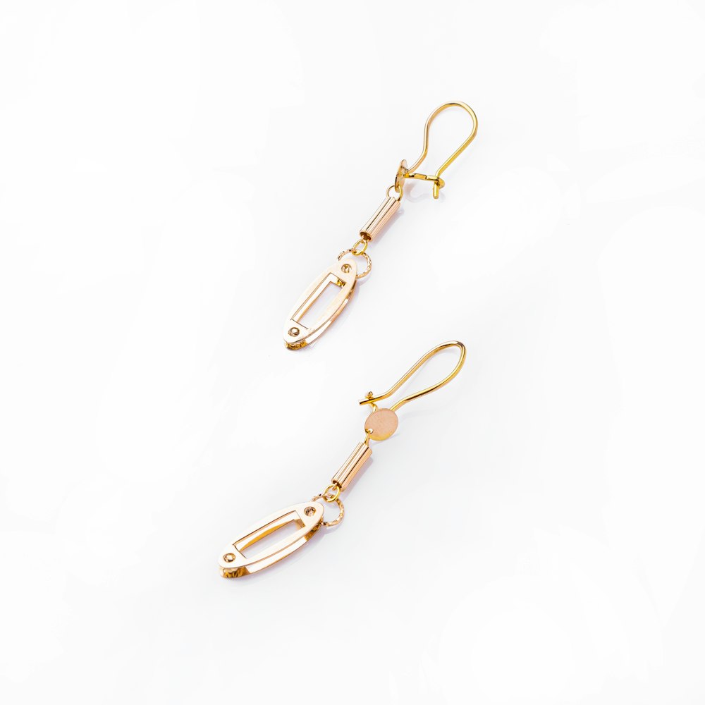 a pair of gold - plated earrings on a white background