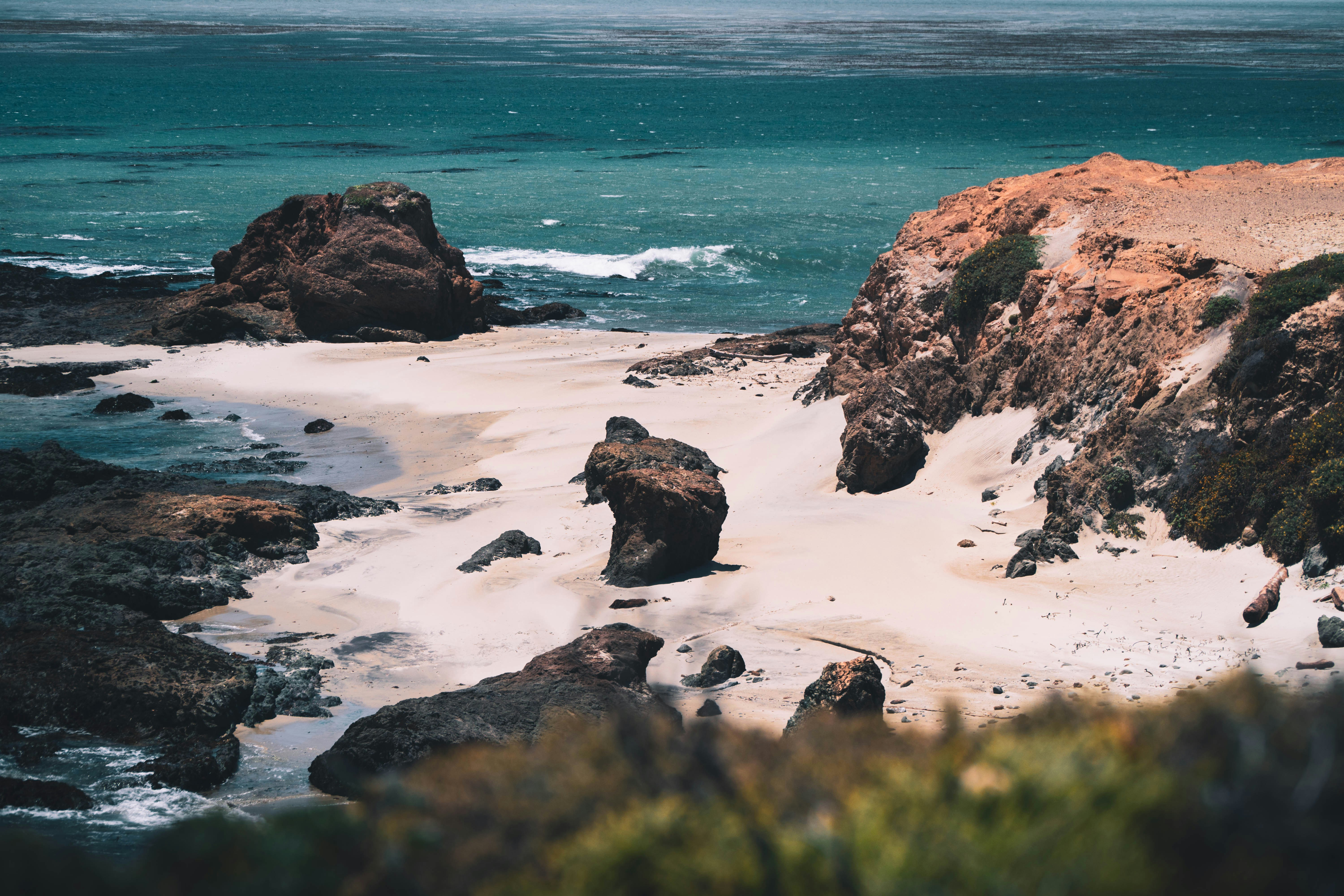 a sandy beach next to a body of water, 