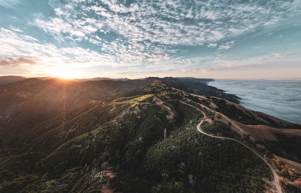 the sun is setting over a mountain with a winding road