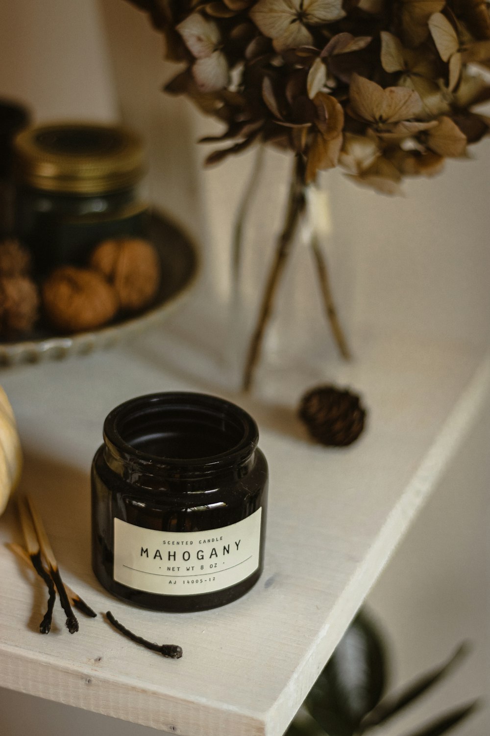 a jar of jam sitting on a shelf next to a vase of flowers