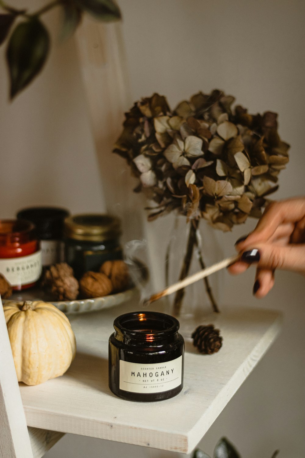 a person holding a spoon over a jar of candles