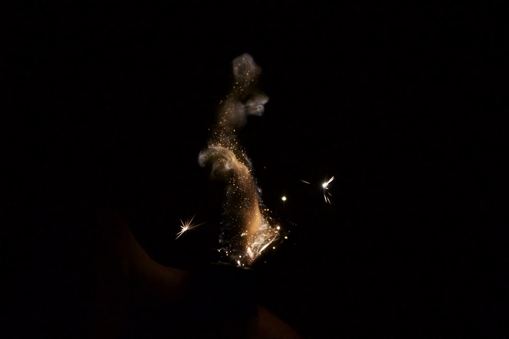 a hand holding a lit candle in the dark