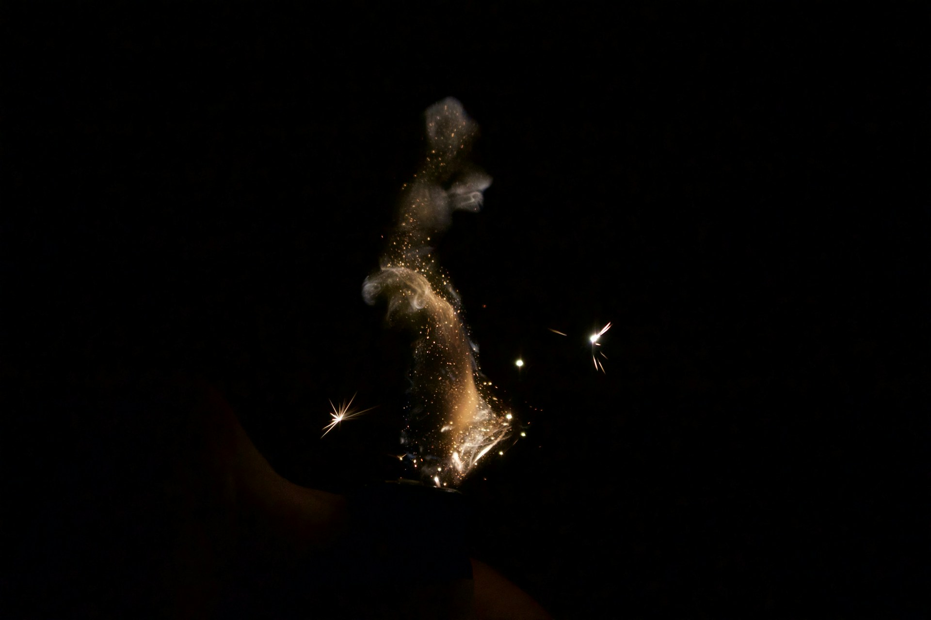 a hand holding a lit candle in the dark