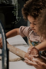a little girl is making a doughnut on a counter