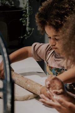 a little girl is making a doughnut on a counter