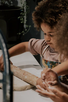a little girl is making a doughnut on a counter