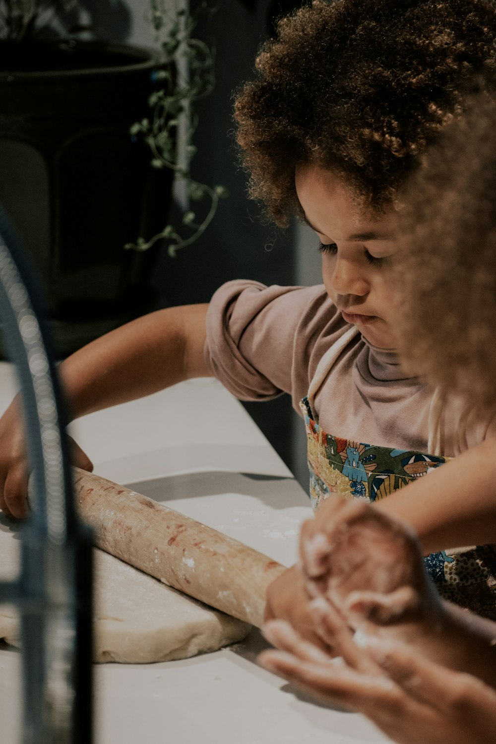 a little girl is making a doughnut on a counter