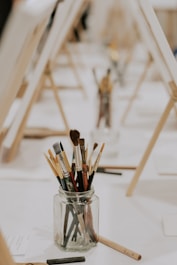 a jar filled with paint brushes sitting on top of a table