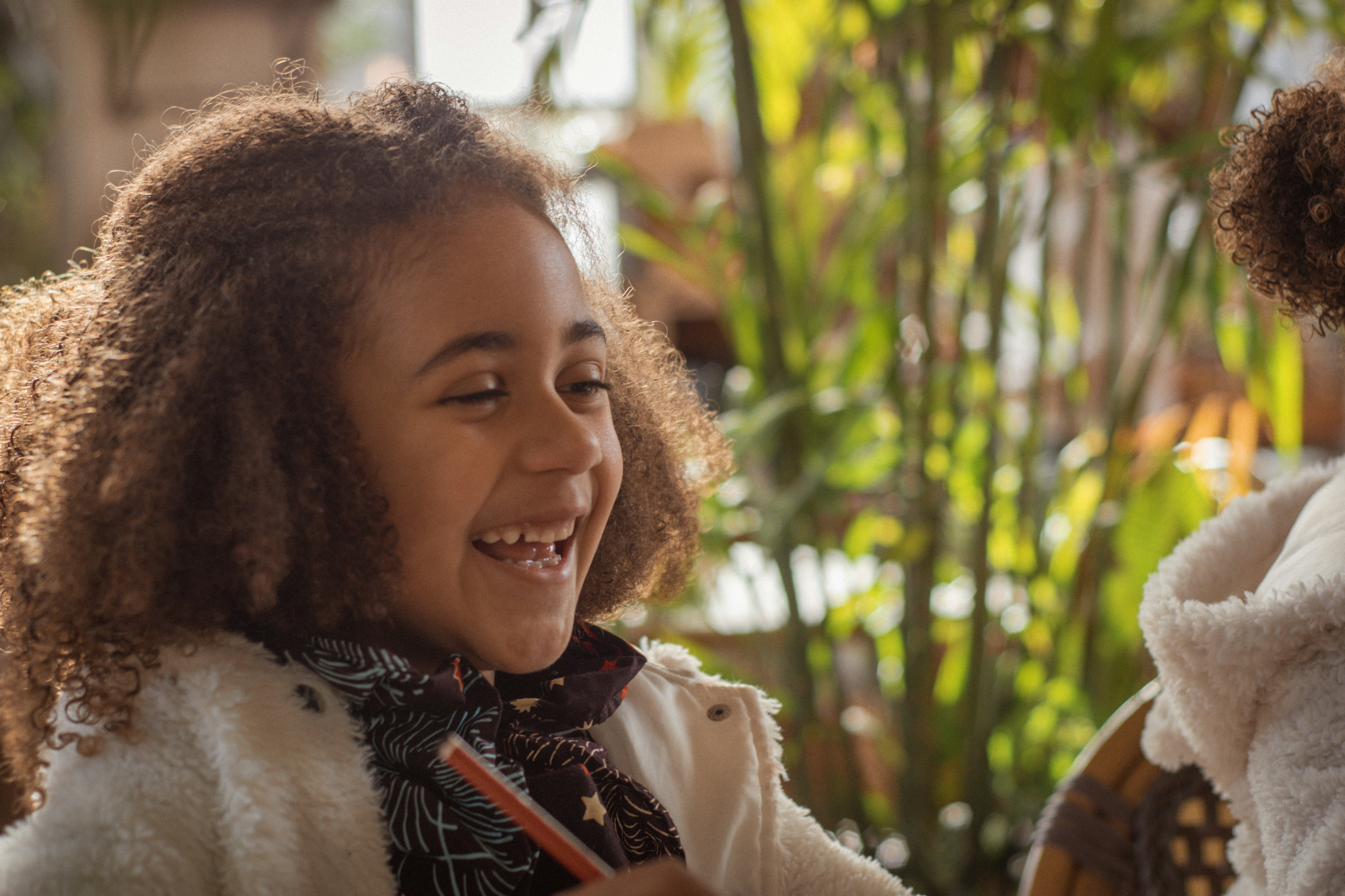 a young girl smiles as she sits next to another young girl