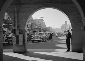 Black and white photo of Enon Valley’s main street bustling with vintage cars and pedestrians.