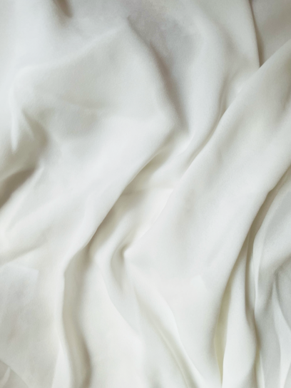 Soft white fabric with gentle, flowing folds, creating a smooth texture.