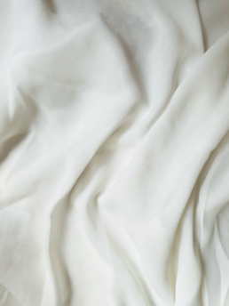 Soft white fabric with gentle, flowing folds, creating a smooth texture.