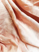 A serene close-up of a delicate floral dress fabric draped softly over a wooden chair in natural light.