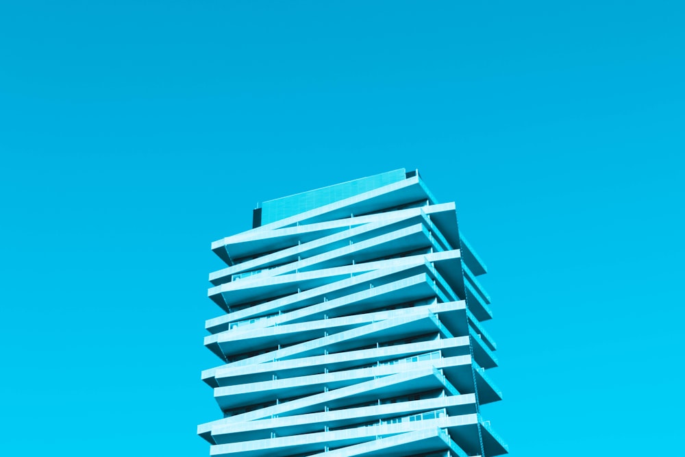 a tall blue building with balconies against a blue sky