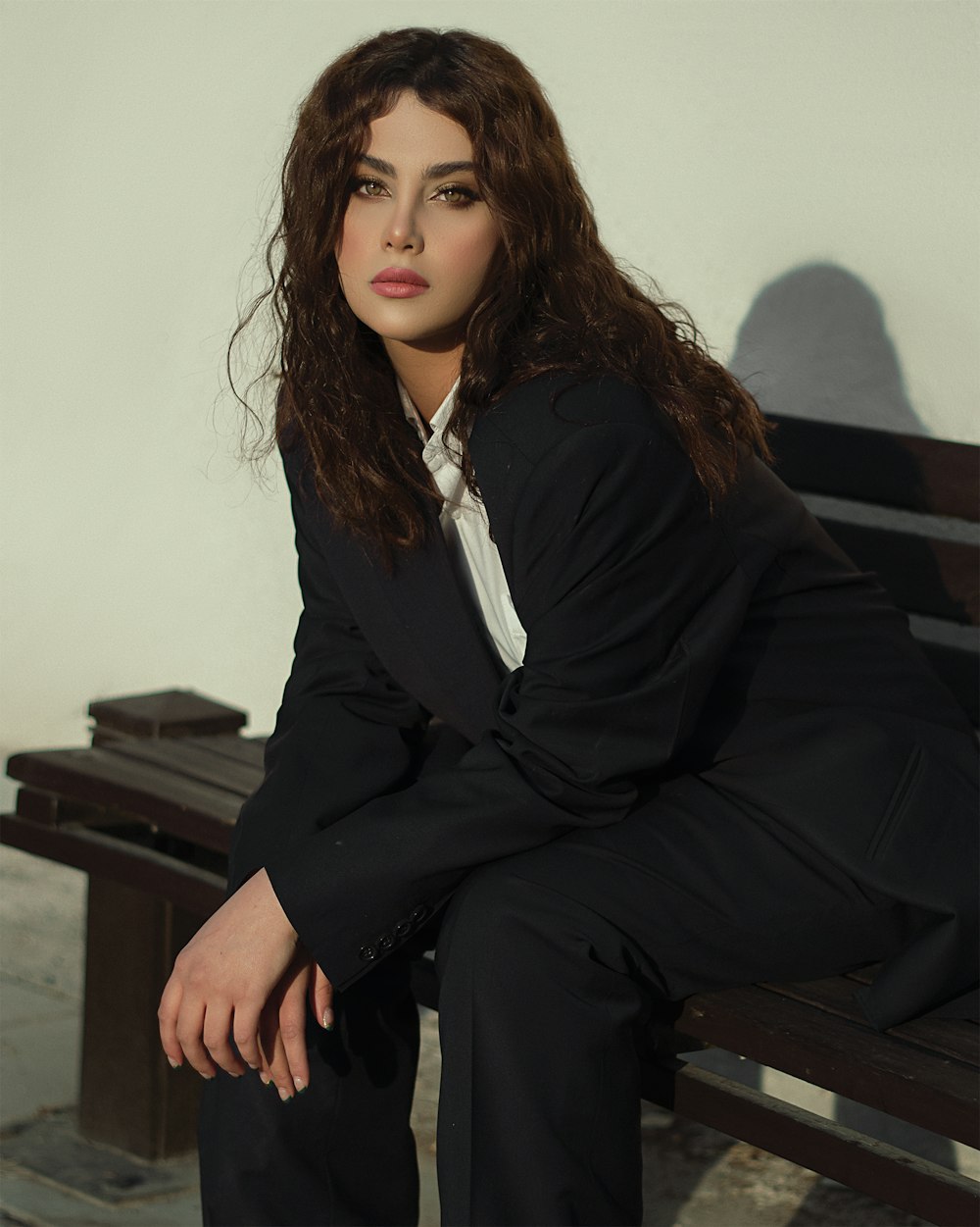 a woman in a suit sitting on a bench