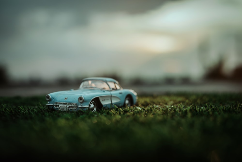 a toy car sitting in the grass on a cloudy day