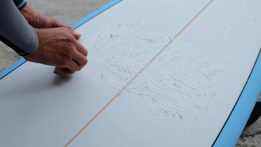 una persona tiene in mano una tavola da surf con una scritta su di essa