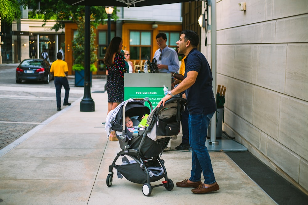 a man standing next to a baby in a stroller