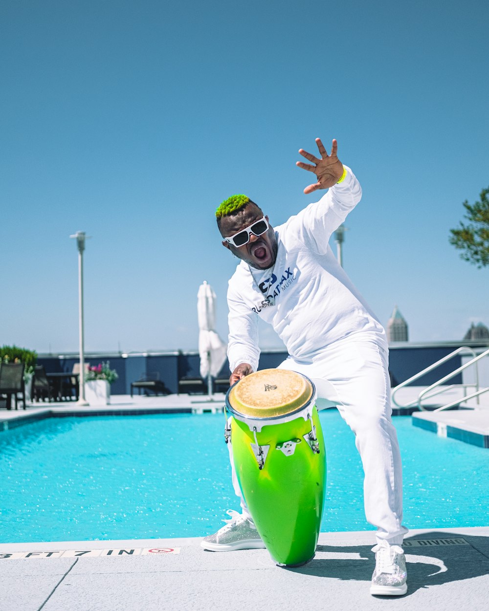 a man in a white suit and sunglasses standing next to a green trash can