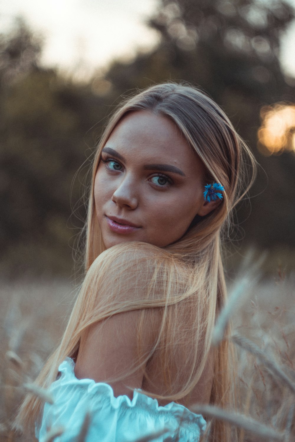 a woman with long blonde hair standing in a field