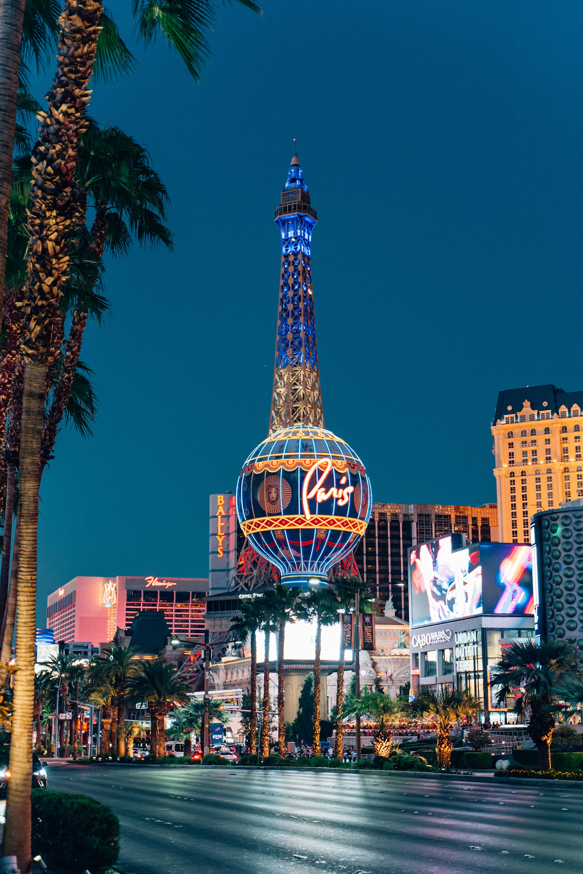 The Las Vegas Strip lit up at night, with a replica Eiffel Tower rising above the boulevard.
