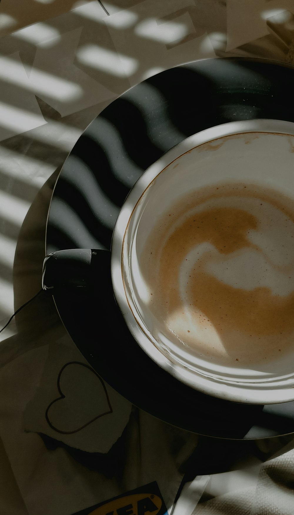 a cup of coffee sitting on top of a black and white plate