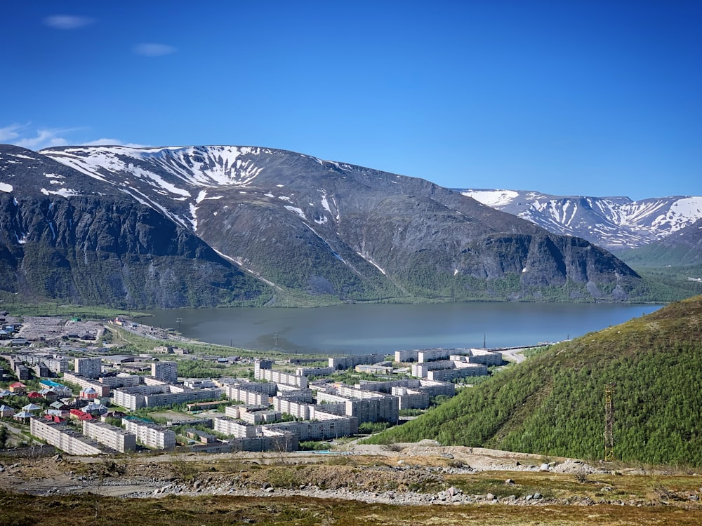 a view of a mountain town with a lake and mountains in the background