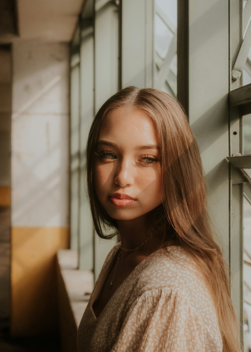 a woman with long hair standing next to a wall