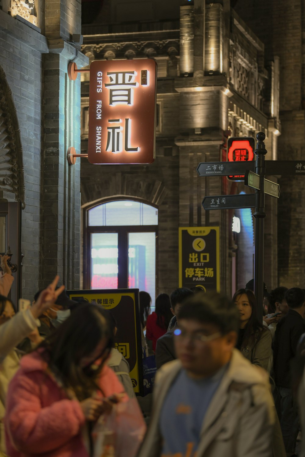 a group of people walking down a street next to tall buildings