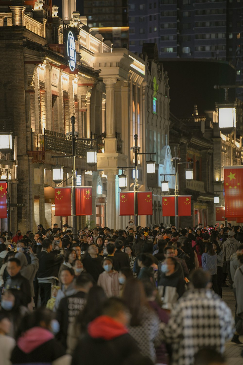 a crowd of people walking down a street at night